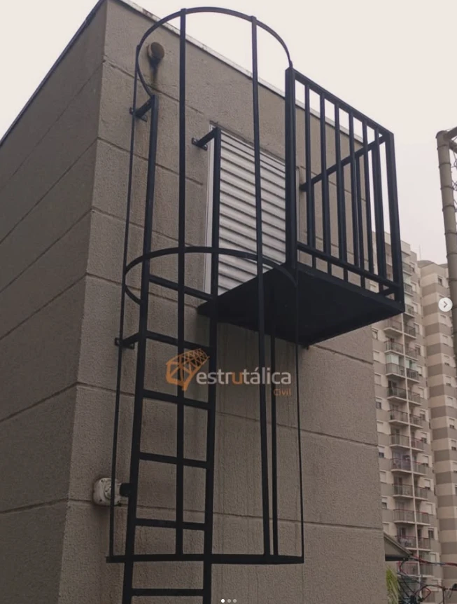 Escada marinheiro preta com guarda-corpo tipo gaiola e plataforma instalada na fachada de um prédio